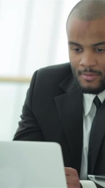 Keskin siyah takım elbiseli kararlı bir işadamı, büyük pencerelerden sızan doğal ışıkla aydınlanan bilgisayarındaki verileri dikkatle analiz ediyor. Odaklanmış tavrı ve profesyonel kıyafeti hırs ve yeniliğin özünü somutlaştırıyor.