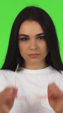 This stunning studio portrait showcases a fierce brunette woman with long hair, confidently gazing at the camera through trendy pink eyeglasses against a vivid green backdrop. Her empowered expression and relaxed pose exude youthful energy and