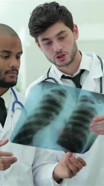 Zarif, iyi ışıklandırılmış bir hastane ortamında üç kendine güvenen doktor ve bir kadın sağlıklı akciğerlerin röntgenini inceliyor. Odaklanmış ifadeleri ve beyaz önlükleri hasta bakımında mükemmelliğe olan bağlılıklarını yansıtıyor.