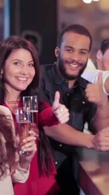 A vibrant gathering of young men and women at the bar, radiating joy as they raise their glasses in a spirited toast. This lively crew, filled with excitement, celebrates their favorite football team while enjoying cold beers, creating unforgettable