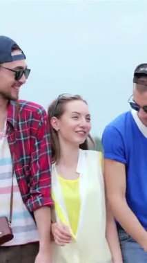 Three cheerful friends, dressed in vibrant summer attire, stroll together under a radiant blue sky, their laughter echoing the carefree spirit of youth. The playful camaraderie and bright colors of their outfits create a lively atmosphere, capturing