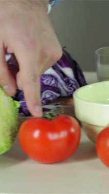 In a lively kitchen, a close-up captures the hands of young friends joyfully chopping vibrant vegetables, including glossy red tomatoes and fresh green cabbage, for a delightful dinner. The scene radiates warmth and laughter, showcasing the joy of