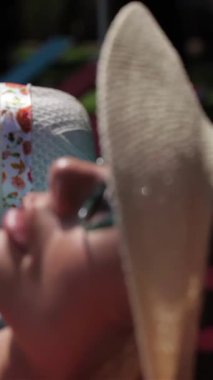 A close-up captures two radiant women, one a fiery redhead and the other a sleek brunette, luxuriating under the sun beside a sparkling swimming pool. Their chic beach hats and stylish sunglasses amplify the vibrant summer atmosphere, radiating joy