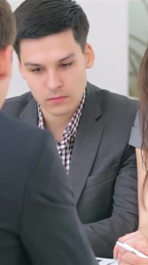 A dynamic young couple, deeply engaged in a business consultation, collaborates with a professional analyst in a bright, modern office. The natural light streaming through the windows highlights their focused expressions and stylish business attire