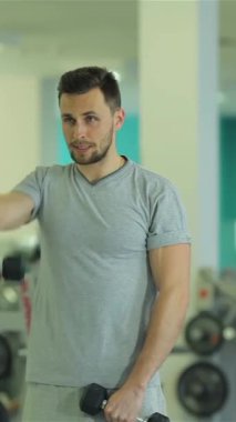 Ortadoğu kökenli kendini adamış genç bir adam triseps egzersizleriyle yoğun bir şekilde meşgul, parlak ve modern bir spor salonunda sarsılmadan dambılları kaldırıyor. Keskin fiziği ve kararlı ifadesi çevresi spor salonuyla çevrili.