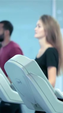 A dynamic group of focused athletes, including a slender girl in a stylish black sports top, are actively adjusting their treadmills in a sleek, modern gym. The vibrant atmosphere buzzes with motivation and energy as they gear up for an exhilarating