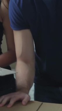 An ecstatic couple, brimming with love, leans over a cardboard box, their faces lit up with surprise and delight as they unveil hidden gems. Surrounded by a flurry of moving boxes in a sunlit, airy room, they capture the essence of adventure and the