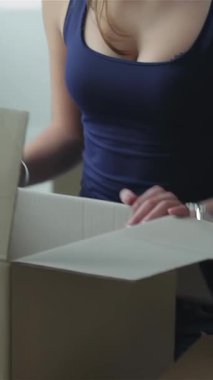 An ecstatic couple, brimming with love and excitement, leans over a cardboard box, their faces glowing with joy as they unveil hidden treasures. Surrounded by a sunlit, airy room filled with moving boxes, they capture the essence of adventure and new