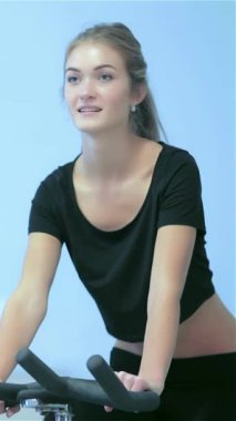 Enerjiyle dolu canlı bir spor salonunda, atletik kızlar hareketsiz bisikletlerle pedal çeviriyor, güçlerini ve kararlılıklarını sergiliyorlar. Birlikte terledikçe atmosfer motivasyonla uğulduyor, somutlaştırıcı takım çalışması ve ortak bir kararlılık.