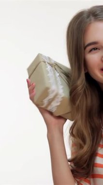 Dalgalı kahverengi saçlı neşeli genç bir kadın güzel bir hediyeyi sevinçle sallıyor. Parlak gülüşü sahneyi saf heyecanla aydınlatıyor. Bu büyüleyici portre sürprizin ve mutluluğun özünü somutlaştırıyor.