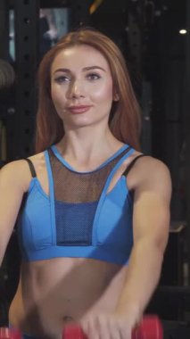 İki enerjik genç kadın parlak kırmızı dambılları neşeyle kaldırıyor parlak, modern bir spor salonunda, güçlerini ve kırılamaz bağlarını sergiliyorlar. Işıl ışıl gülüşleri ve enerjik tavırları pozitiflik ve motivasyon yayıyor, sağlıklı bir ruhun özünü somutlaştırıyor.