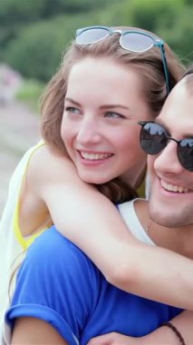 Neşeli genç bir kadın, neşeli bir şekilde gülümseyen ortağına arkadan sarılıyor, ikisi de açık havada güneşli bir günün tadını çıkarırken neşe saçıyor. Enerjik enerjileri ve sevgi dolu bağları dostluk ve aşkın özünü vurguluyor, yürek ısıtan bir sahne yaratıyor.