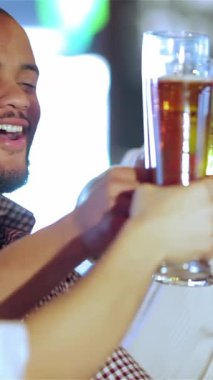 Neşeli dört iş adamı, ışıl ışıl gülümseyen gülümsemeleriyle canlı bardaklarını canlı bir barda kaldırarak televizyondaki bir futbol maçının heyecanını kutluyorlar. Canlı atmosfer kahkaha ve yoldaşlıkla uğulduyor, renkli ışıklarla aydınlatılıyor, tost yaparken