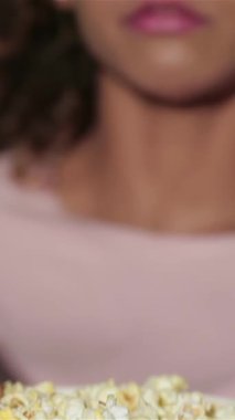 Çekici kıvırcık saçlı bir kız bir avuç patlamış mısırın tadını çıkarıyor, geniş gözleri, loş, loş bir sinemada titreyen perdeye sabitlenmiş. Hayat dolu atmosfer, arkadaşlar ve çiftler arasında paylaşılan kahkahalarla doludur.