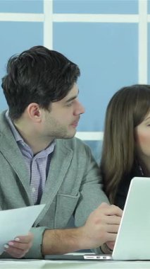 Parlak ve modern bir ofiste, tutkulu bir proje yöneticisi, tartışmayla tamamen meşgul olan ilgili meslektaşlarına coşkulu bir rapor sunuyor. Geniş pencereler alanı doğal ışıkla doldurarak ilham verici bir şey yaratıyor.