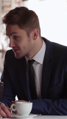 Üç iyi giyimli adam şık bir kafede iş yemeği sırasında canlı bir tartışmaya giriştiler, kahve ve tablet içerek fikir alışverişinde bulundular. Animasyon ifadeleri ve yoldaşlıkları başarılı bir ortaklığı, takım çalışmasını ve işbirliğini yansıtıyor.