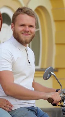 Neşeli genç bir çift, mutluluk saçan, güneşli bir cadde boyunca klasik bir scooter süren, tasasız yaz maceralarının özünü somutlaştıran. Işıldayan gülümsemeleri ve rahat tavırları, canlı renklerle çerçevelenmiş keyifli bir yolculuğu yansıtıyor.