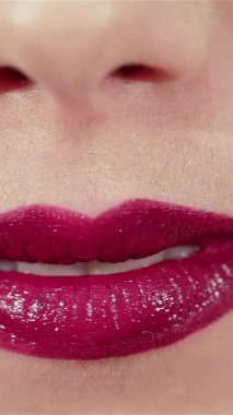 A mesmerizing close-up captures a stunning Caucasian woman blowing a kiss, her luscious lips painted in a sparkling red hue that radiates under soft, flattering lighting. This enchanting image showcases her flawless skin and captivating expression