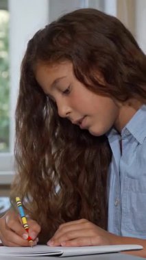 A thoughtful young girl with flowing brown hair gazes dreamily into the distance, her creativity ignited as she crafts her art project at school. Surrounded by vibrant art supplies, she radiates the joy of childhood imagination and the thrill of