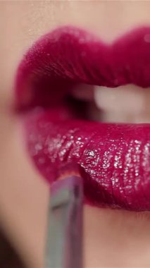 This stunning close-up captures the allure of a brunette woman, her radiant smile accentuated by glossy, vibrant red lips. The meticulous detail highlights the texture of her lips, exuding confidence and sophistication in a pristine studio backdrop