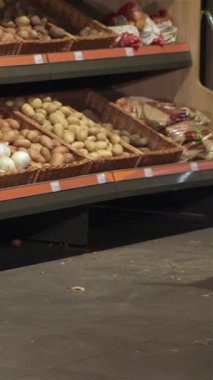 A joyful young couple strolls through a bustling supermarket, pushing a trolley brimming with fresh, colorful vegetables. The woman, dressed in stylish denim, shares a delightful moment with her boyfriend, who walks closely beside her, radiating