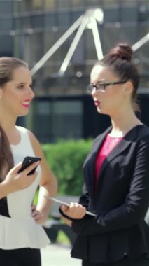 In a bustling urban landscape, a confident young businesswoman expertly navigates her tablet, while her colleagues engage in animated discussion nearby. This vibrant scene encapsulates the spirit of modern collaboration, highlighting the synergy of