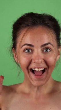 A beaming young woman radiates pure joy, her infectious laughter illuminating the vivid green chromakey background. Her playful pose and charming smile capture a moment of carefree happiness, inviting everyone to share in her exuberance and sense of