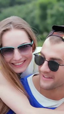A cheerful young man joyfully snaps photos of his stylish friends, basking in the warm sunlight. Their laughter and playful poses radiate a lively atmosphere, celebrating friendship and unforgettable summer memories