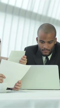 In a bright, contemporary office, four dynamic businessmen engage in an animated discussion around a stylish table, radiating enthusiasm and collaboration. Their confident expressions and professional attire, complemented by laptops and documents