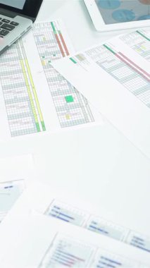 A focused young businessman, with a confident smile, diligently types on his laptop, surrounded by vibrant charts and detailed documents. This lively scene embodies the spirit of teamwork and strategic planning, highlighting the collaborative energy