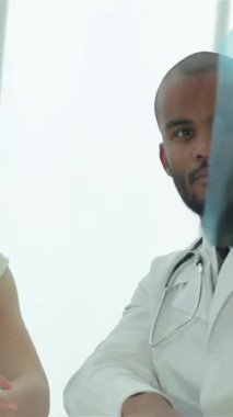 In a bright, modern clinic, a focused doctor in a white coat holds a chest X-ray while engaging in a serious discussion with an attentive patient. The atmosphere radiates professionalism and care, emphasizing the critical importance of lung health