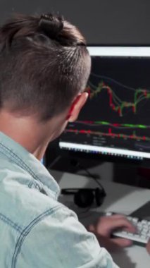 A young male programmer smiles brightly at the camera while deeply engaged in his late-night coding session, surrounded by the glow of multiple screens displaying vibrant data. The dynamic visuals on his monitor and his enthusiastic demeanor create