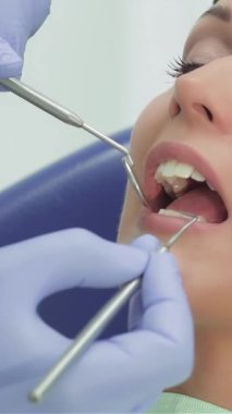 Neşeli genç bir kız, parlak, davetkar bir klinikte ışıldayan profesyonel aletlerle çevrelenmiş diş kontrolünden geçerken ışıl ışıl bir gülümsemeyle ışıldıyor. Bu canlı sahne, oral sağlığın korunması ve özgüvenin gösterilmesi sevincini vurguluyor.