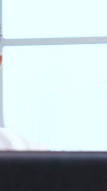 A handsome bearded male manager is deeply engrossed in his work, typing intently on a sleek laptop in a bright, stylish office. The warm tones of the contemporary interior enhance the professional vibe, radiating ambition and productivity