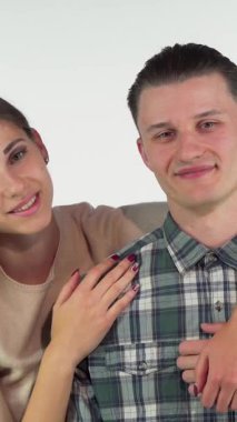 A charming young couple shares a tender embrace, their eyes locked in a gaze filled with warmth and love. The stunning woman, with her soft smile and elegant style, wraps her arms around her handsome boyfriend, creating an intimate atmosphere that