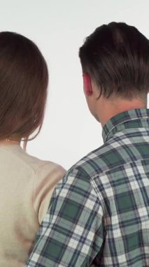 A delightful rear view of a young couple embracing, turning to the camera with beaming smiles that radiate warmth and affection. Their cozy connection captures the essence of romance and happiness, inviting viewers to share in their joyful moment