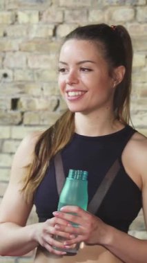 Three fit women share a joyful moment at the gym, animatedly chatting after an invigorating workout. Their vibrant sportswear, glowing smiles, and the warm, textured backdrop create an atmosphere of camaraderie and empowerment, celebrating their