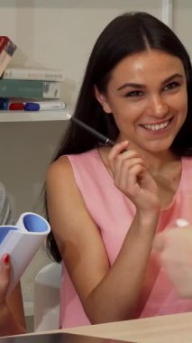 In a modern office filled with books and colorful notes, two young businesswomen passionately exchange ideas, radiating enthusiasm and creativity. Their animated discussion reflects a vibrant atmosphere of collaboration, where innovation and teamwork