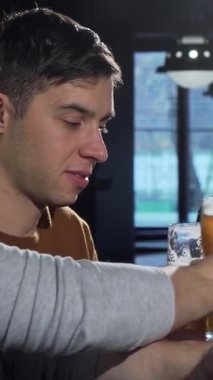 A bearded man joyfully clinks glasses with friends, savoring the rich flavors of craft beer in a cozy bar setting. The warm glow of the ambient lighting and the sound of laughter create an inviting atmosphere, perfect for celebrating friendship and