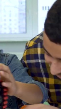 An enthusiastic father and his young son, both African American, share a delightful moment as they examine a vibrant toy tracked ATV. Set against the backdrop of a beautifully adorned Christmas tree, this heartwarming scene radiates the spirit of