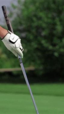 A close-up of a determined young redhead woman in a sleek golf outfit, expertly aligning her putter with the ball on a vibrant green course. Her athletic stance and striking red shoes radiate passion and precision, embodying the excitement of summer