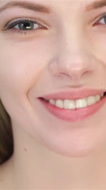 A radiant young blonde woman flashes a dazzling, toothy smile, her fresh skin glowing against a pristine white backdrop. This close-up portrait captures her vibrant confidence and natural beauty, highlighting the gentle curve of her lips and the