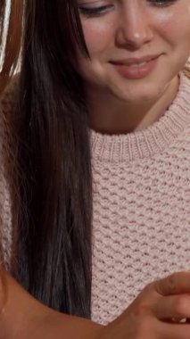 In a cozy coffee shop, two beautiful female friends share laughter and joy as they browse a vibrant red smartphone, surrounded by steaming cups of coffee and a flaky croissant. The warm ambiance, filled with the aroma of freshly brewed coffee