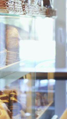 A charming young man with a beaming smile eagerly inspects a vibrant display of mouthwatering pastries in a sunlit bakery. His delight in choosing sweet treats radiates warmth, surrounded by the inviting aroma of freshly baked goods