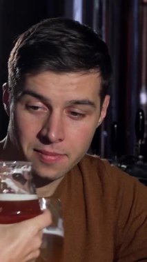 A joyful woman radiates happiness as she beams at the camera, her boyfriend sipping a refreshing beer beside her in a cozy pub. This vibrant scene encapsulates the warmth of love and celebration, perfect for romantic outings or special anniversaries