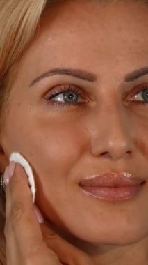 A radiant mature woman with luminous skin beams joyfully as she softly wipes her face with a cotton pad, set against a vibrant green chromakey background. This captivating image embodies the essence of a refreshing skincare routine, emphasizing the