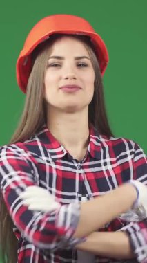 Canlı, genç bir inşaat işçisi kolları çaprazlanmış, grevli bir ekose gömlek ve parlak turuncu bir başlıkla canlı yeşil bir kromakey arka planda duruyor. Işıl ışıl gülüşü ve dengeli tavrı güçlenmeyi ve...