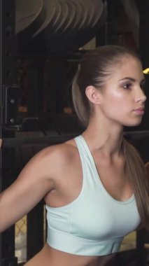 Çarpıcı bir atletik kadın halterle güçlü çömelmeler sergiliyor. Parlak ve modern bir spor salonunda güç ve kararlılık yayıyor. Cilalı siyah ekipman ve yoğun odaklanma onun fitness yolculuğunun enerjisini arttırıyor.