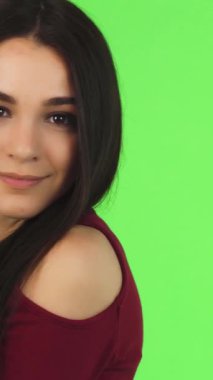 Göz kamaştırıcı bir yakın plan. Uzun, dalgalı siyah saçları olan, çarpıcı yeşil arka planda neşeyle gülümseyen genç bir kadın. Bulaşıcı mutluluğu ve kendine güveni sahneyi aydınlatıyor, izleyicileri pozitifliği ve kendini ifade etmeye davet ediyor.