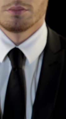 Pürüzsüz siyah takım elbiseli ve beyaz gömlekli genç beyaz bir adam dramatik bir siyah arka plana karşı cesurca duruyor ve şiddetli bir meydan okuma jesti ile yumruğunu kaldırıyor. Onun haşin, tıraşsız yüzü ve delici bakışları... yoğunluk ve kararlılık saçıyor.